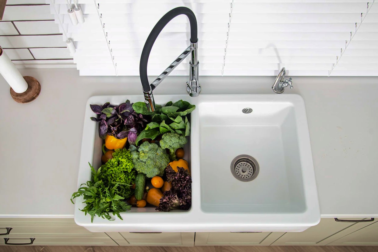 Variety of vegetables in the kitchen sink of modern kitchen close up.